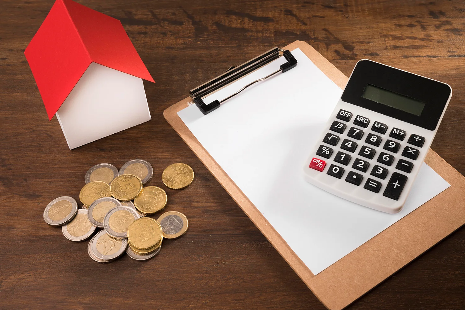 Property tax calculation with house model, calculator, and coins, representing professional property tax protest services by Tax Cutter.