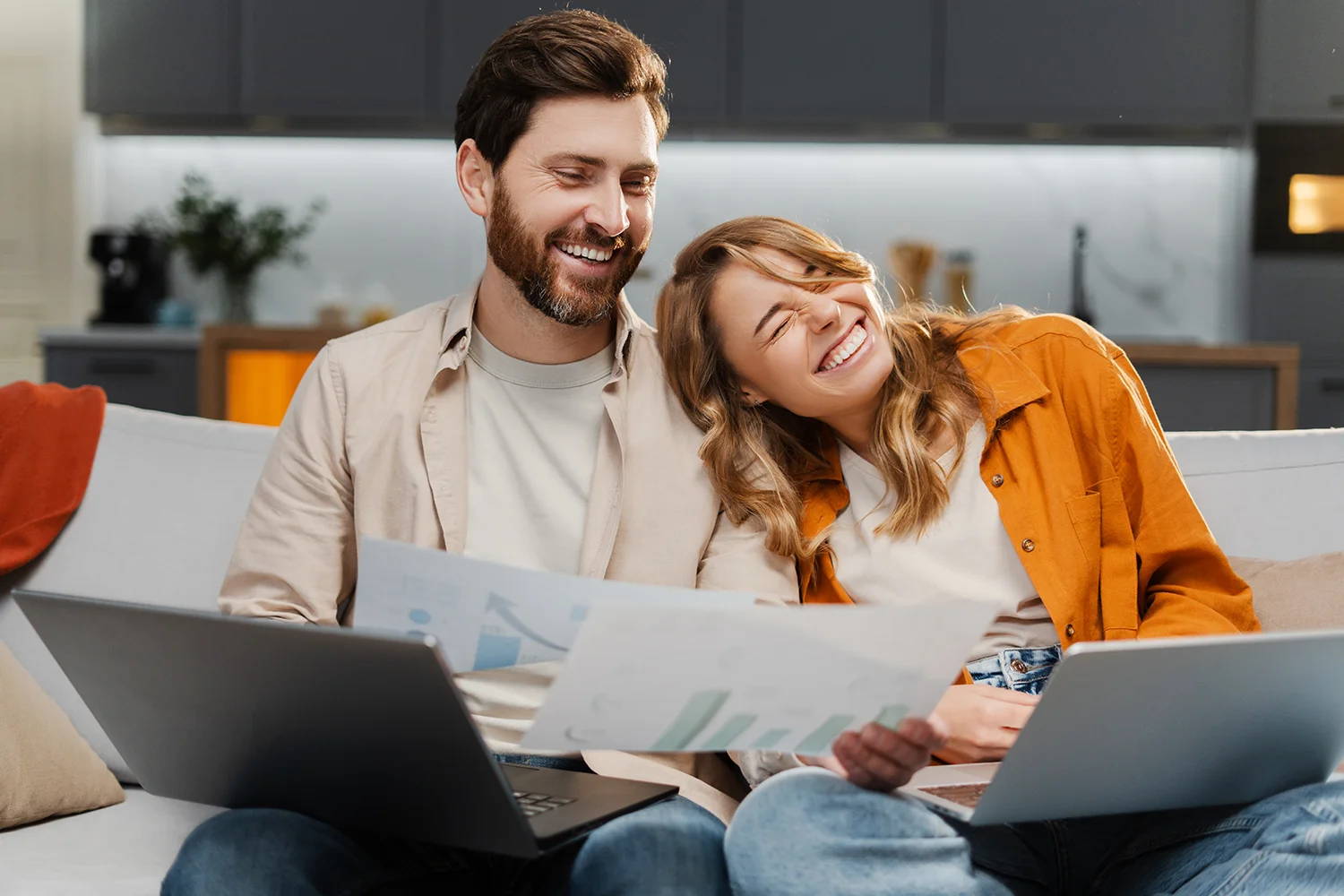 Happy homeowners reviewing property tax documents on laptops at home, showing successful property tax savings after a professional tax protest with Tax Cutter.