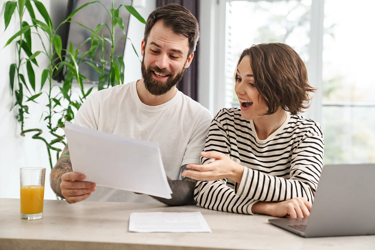 Happy homeowners reviewing property tax documents together at home, showing savings from Texas property tax protest services by Tax Cutter.