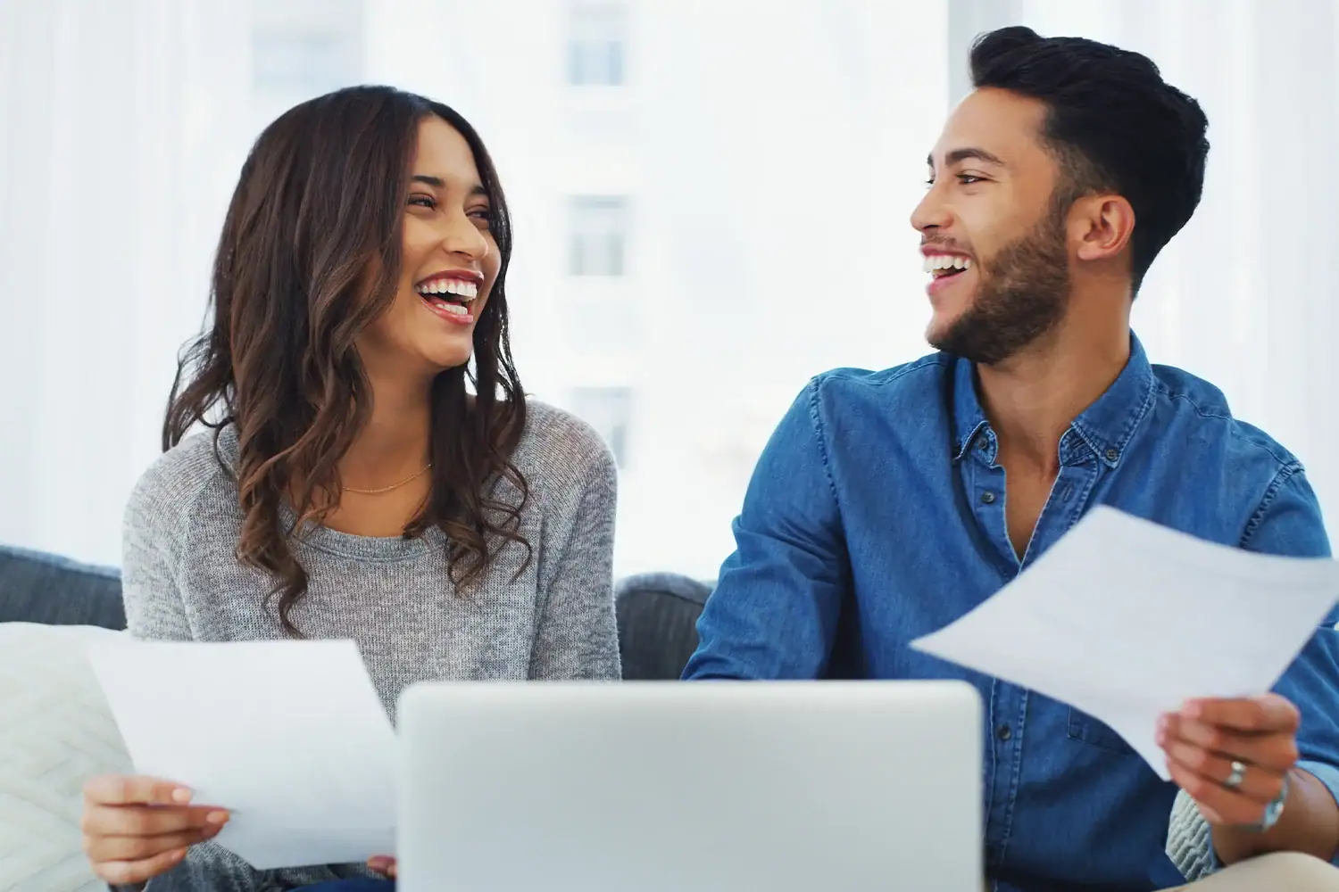 Happy couple reviewing property tax appeal documents at home using laptop, showing savings from Houston tax protest services by Tax Cutter.