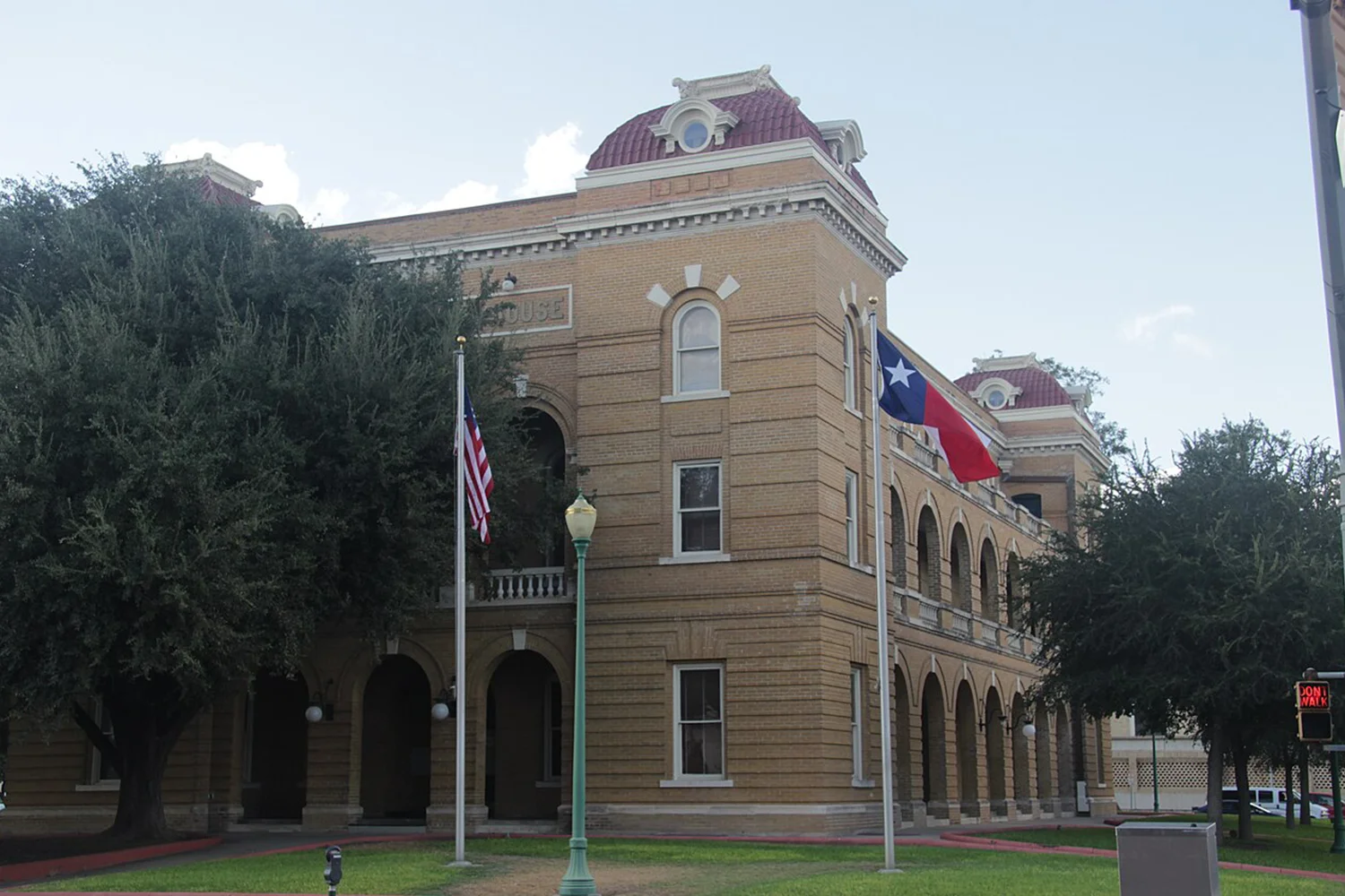 Webb County Courthouse in Texas with U.S. and Texas flags, representing Houston property tax protest services by Tax Cutter