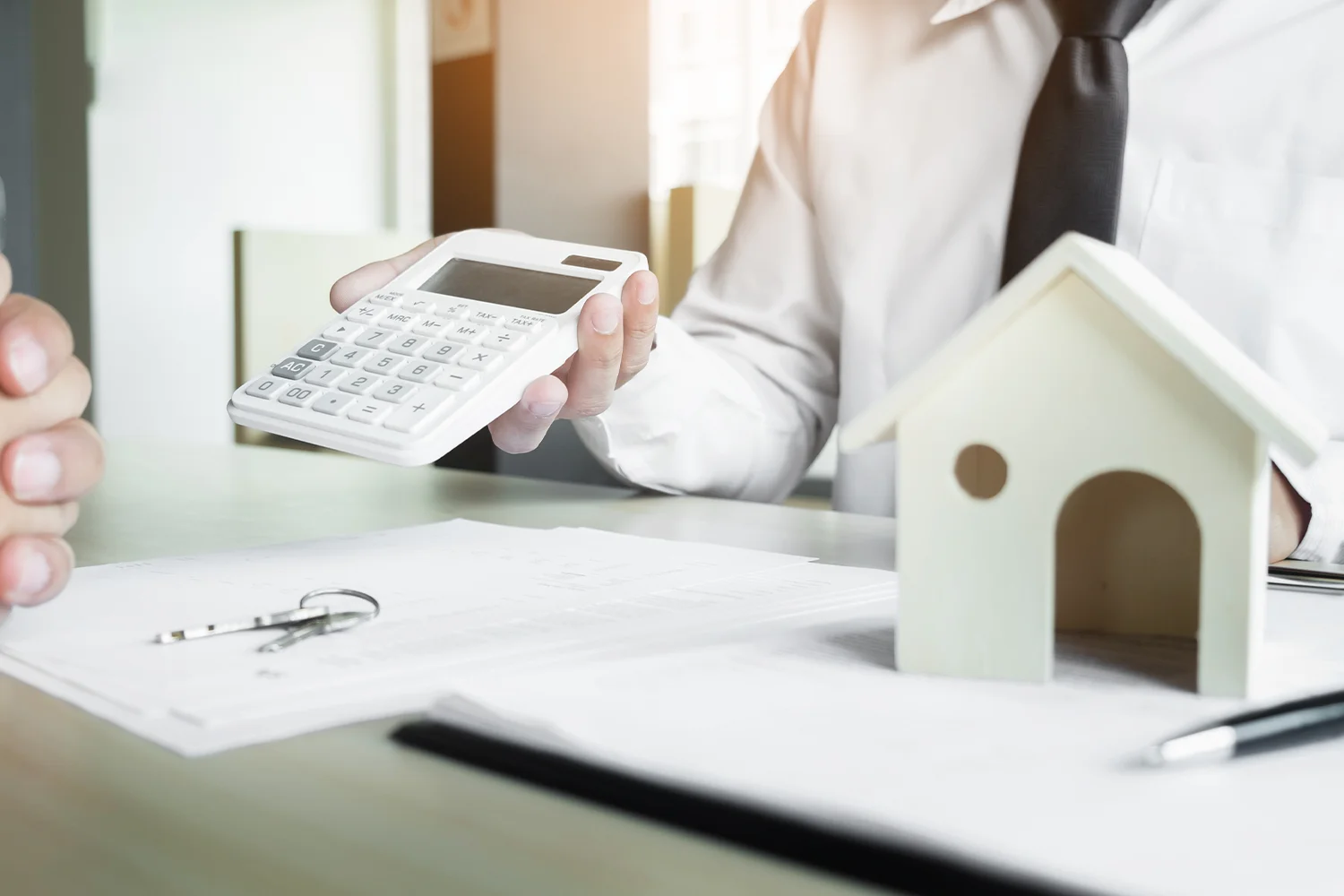 Property tax consultant calculating Houston home tax assessment with calculator and house model for Tax Cutter protest services.