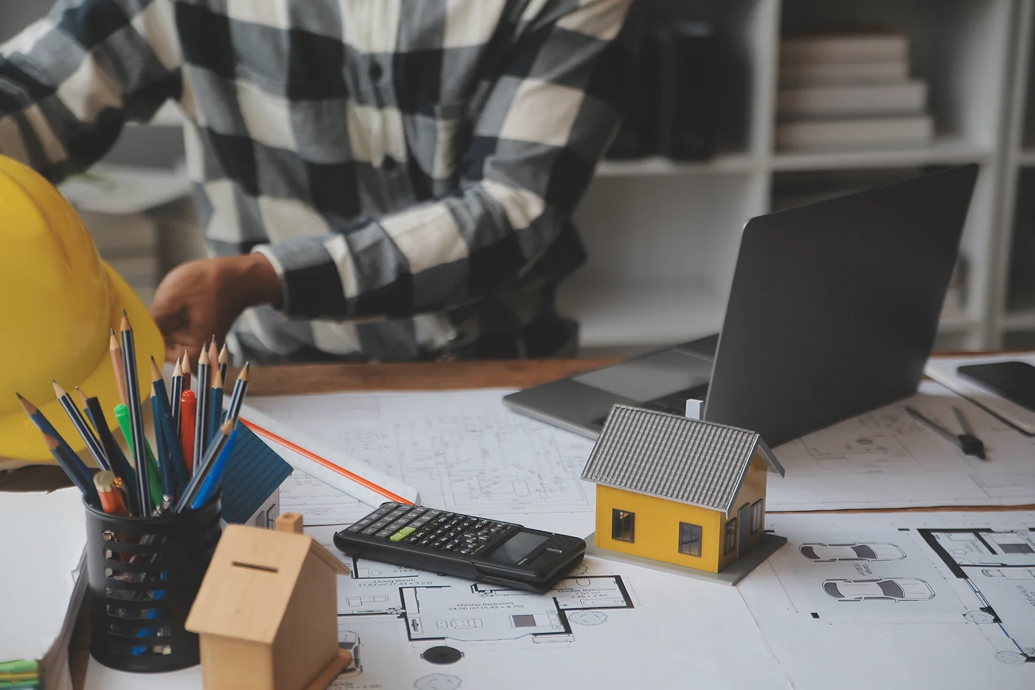 Property owner reviewing home blueprints with calculator and laptop, preparing for property tax protest and assessment review.