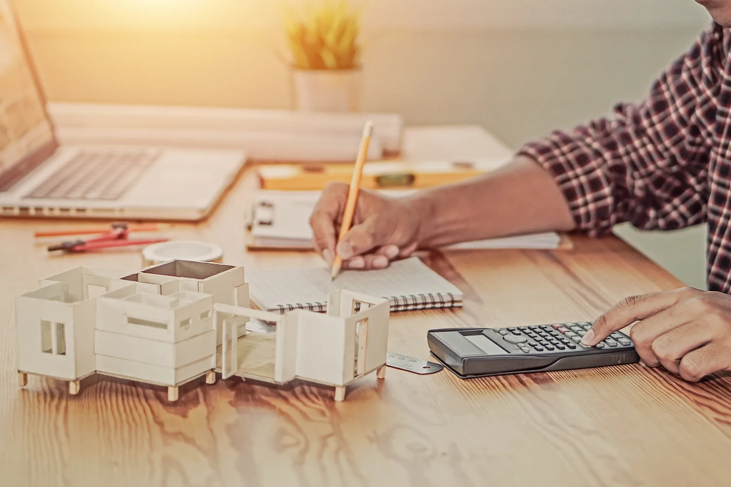 Homeowner calculating property taxes with house model and calculator, representing Houston property tax protest services by Tax Cutter. 