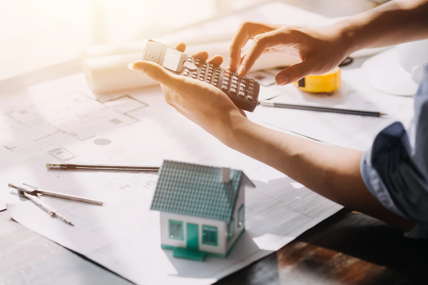 Homeowner calculating property taxes with calculator and house model, representing Houston property tax protest services by Tax Cutter.