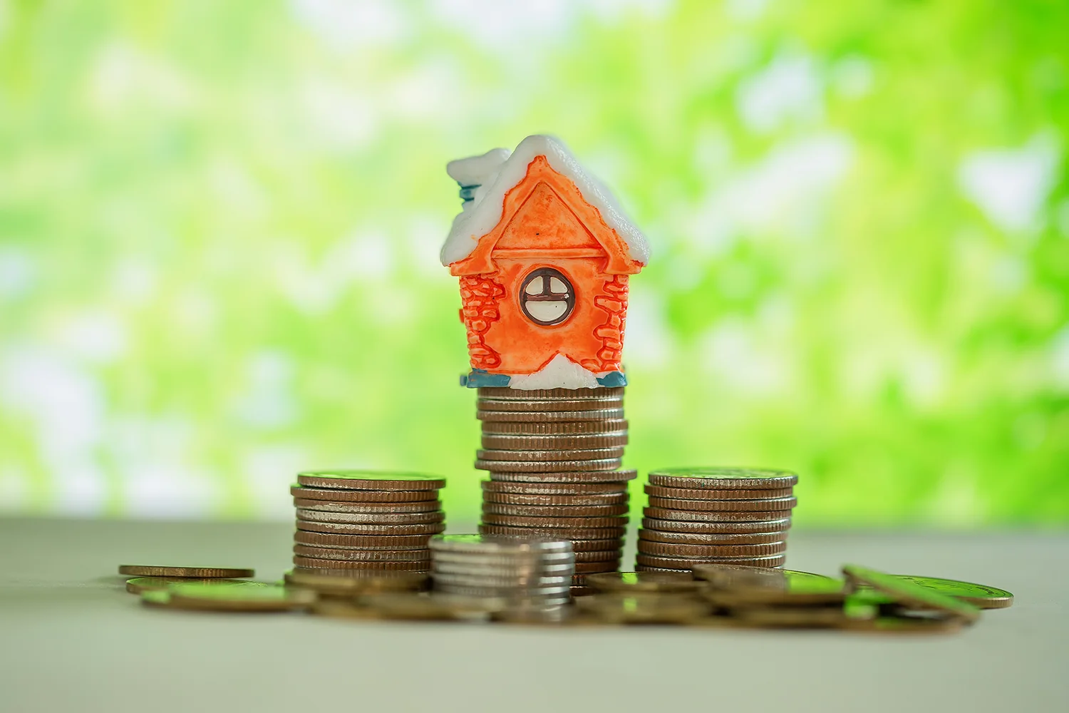 House model on stacked coins representing Houston property tax savings through professional property tax protest by Tax Cutter