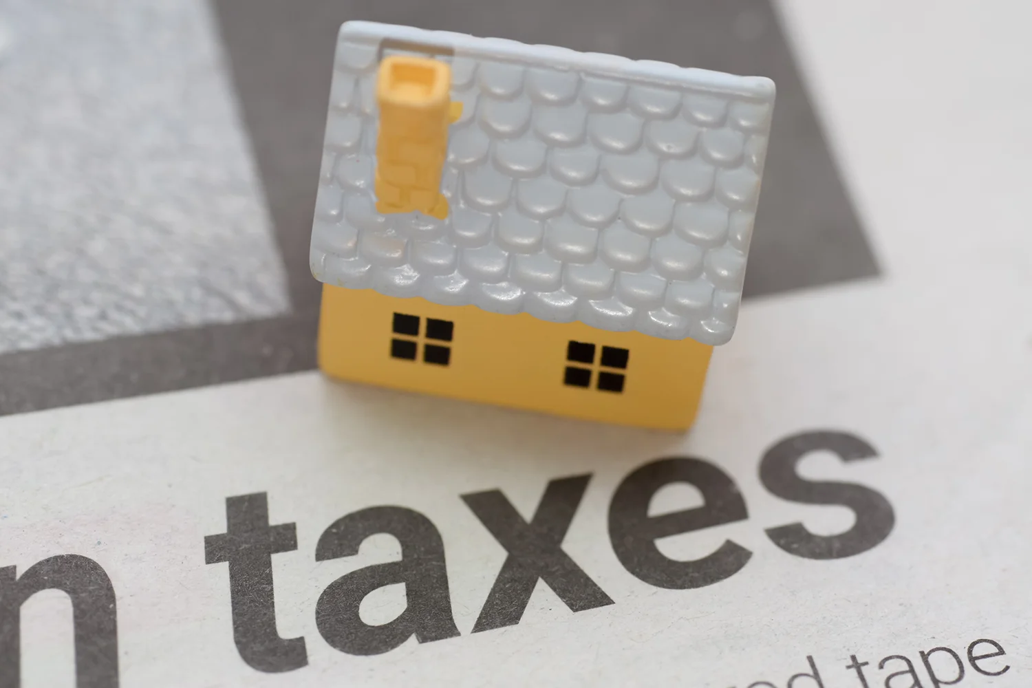 Miniature house on top of "taxes" document, symbolizing property tax issues and the services of Tax Cutter in helping homeowners reduce taxes in Houston.