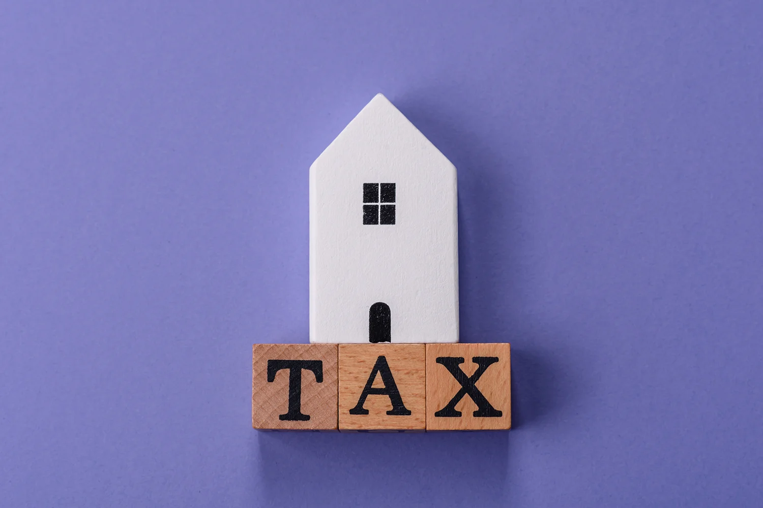 House model above wooden blocks spelling TAX, symbolizing Houston property tax protest and appeal services by Tax Cutter.