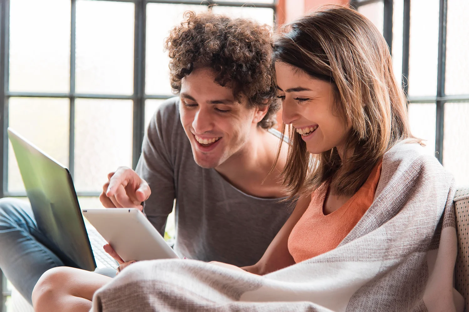 Happy couple reviewing property tax protest results on a laptop and tablet, symbolizing successful property tax reduction with Tax Cutter’s services. 