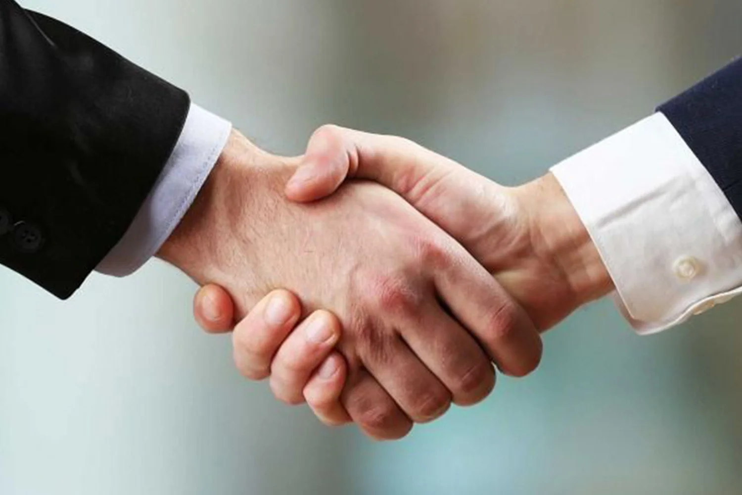 Two business professionals in formal attire shaking hands, symbolizing agreement, trust, and partnership