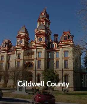 Historic Caldwell County Courthouse in Texas with ornate architecture and tall towers, set against a clear blue sky.