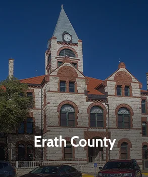 Erath County Courthouse in Texas with red brick and stone facade, tall clock tower, and historic design in a downtown setting.