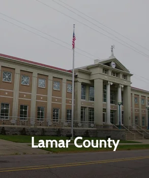 Lamar County Courthouse in Texas with stone facade, tall columns, and arched entrances showcasing historic government building design.