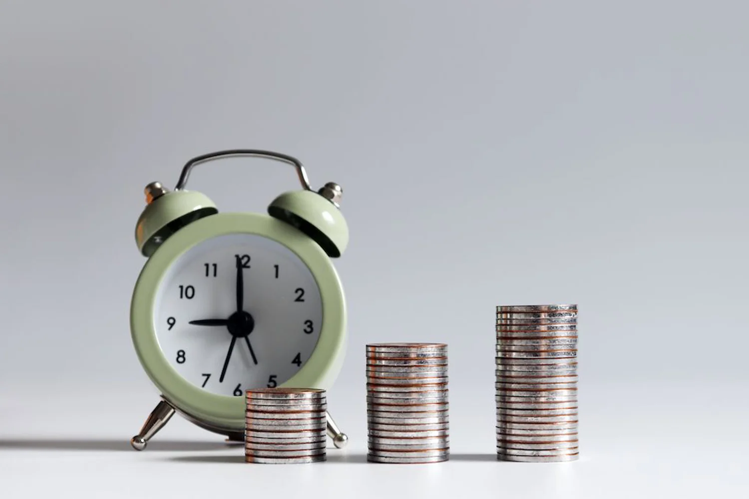 Alarm clock beside stacked coins increasing in height, symbolizing property tax savings, financial growth, and long-term cost reduction.