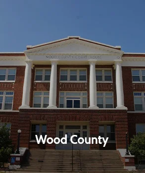 Wood County Courthouse in Texas featuring red brick architecture, tall white columns, and a grand staircase leading to the main entrance.